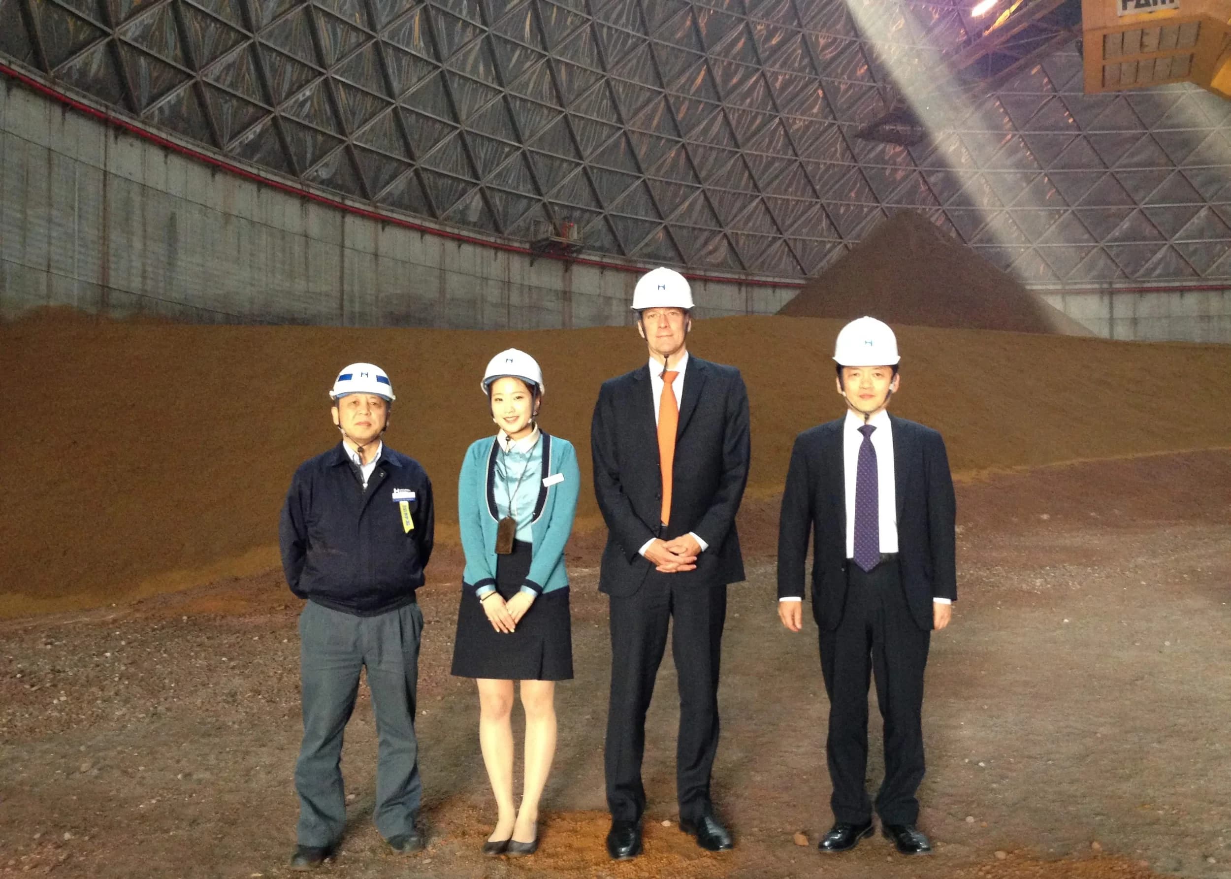 Geoffrey Kirkman in a hard hat with a Hyundai Steel site team, inside a raw material dome